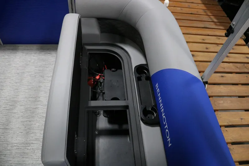 Slide: The Image of 2025 Bennington 22 S STERN RADIUS boat seat storage compartment, open on wooden deck. - 18