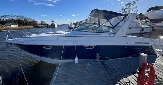 Slide: The Image of 2003 Formula 27 PC boat docked at marina, blue and white exterior. - 2