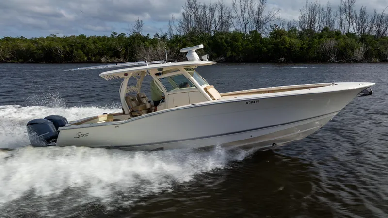 Slide: The Image of 2012 Scout 345 XSF boat cruising on a river with lush greenery. - 0