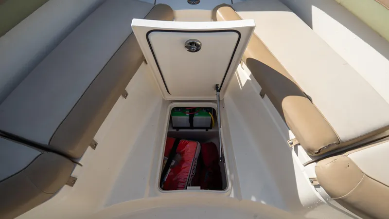 Slide: The Image of Open storage compartment on 2012 Scout 345 XSF boat with beige seating. - 20