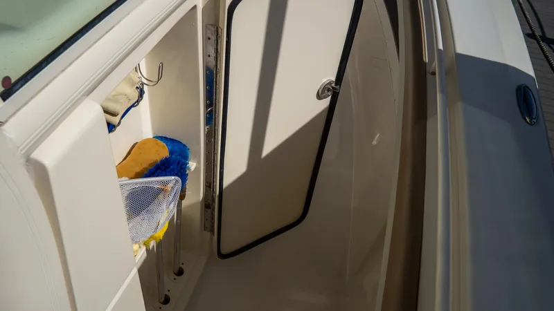 Slide: The Image of Open storage compartment on 2012 Scout 345 XSF boat with cleaning supplies. - 44