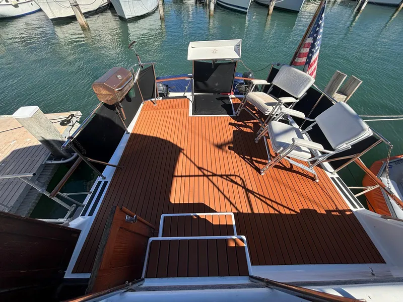 Slide: The Image of 1979 Ocean Yachts Trawler deck with chairs, grill, and American flag at marina. - 12
