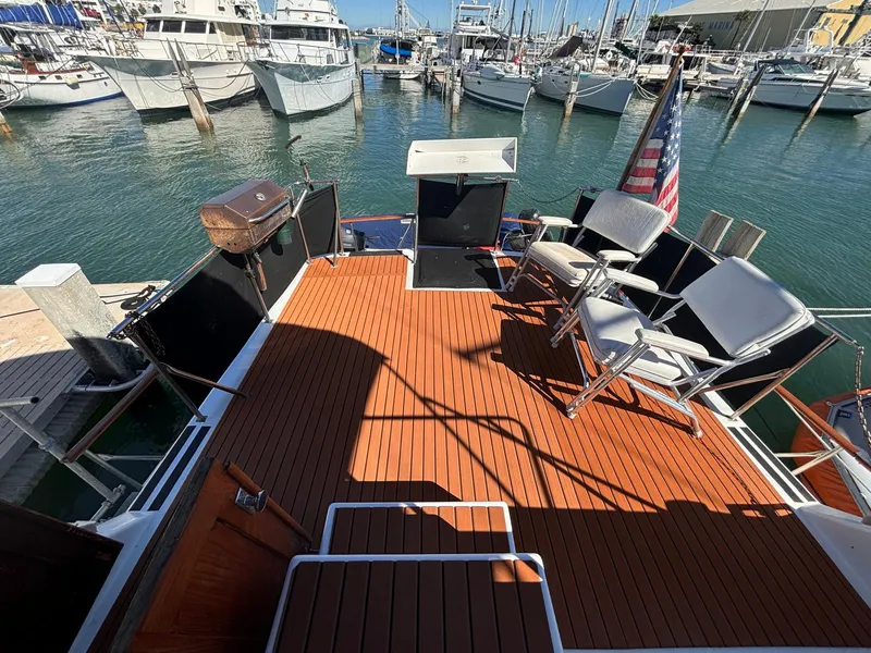 Slide: The Image of 1979 Ocean Yachts Trawler deck with chairs, grill, and American flag in marina. - 13