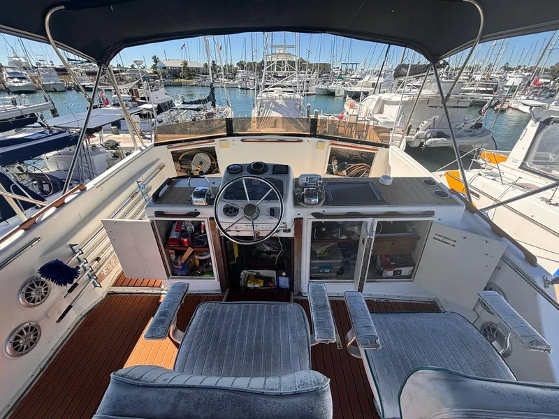 Slide: The Image of 1979 Ocean Yachts Trawler helm with marina view, featuring dual seats and navigation controls. - 16