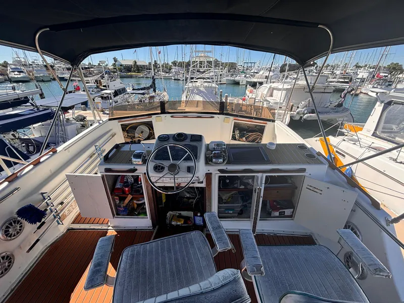 Slide: The Image of 1979 Ocean Yachts Trawler helm with marina view, featuring navigation equipment and seating. - 17