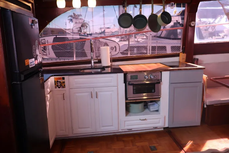 Slide: The Image of 1979 Ocean Yachts Trawler kitchen with modern appliances and hanging cookware. - 28