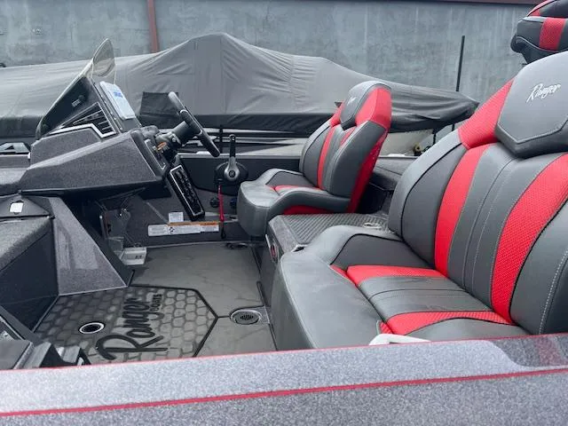 Slide: The Image of 2025 Ranger Z519R boat interior with red and gray seats, steering console, and covered equipment. - 8