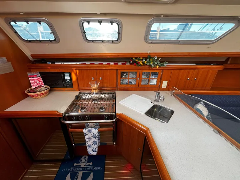 Slide: The Image of 2005 Hunter 41 yacht interior kitchen with stove, sink, and wooden cabinetry. - 25