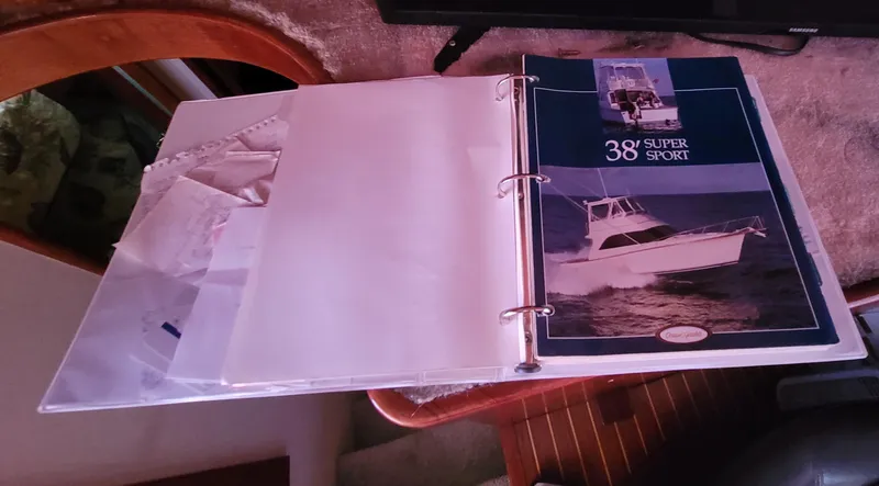 Slide: The Image of Binder with 1988 Ocean Yachts 38 Super Sports brochure on a wooden table. - 21