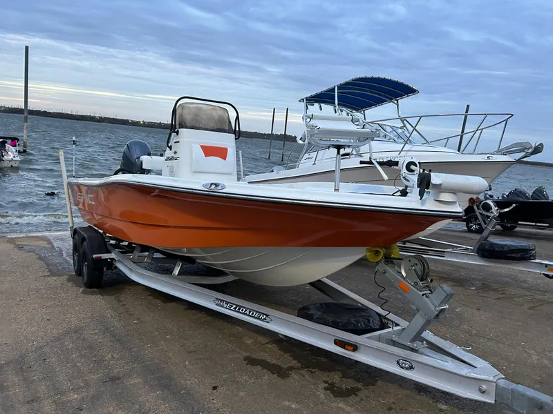 Slide: The Image of 2013 Epic 22 SC boat on trailer by the water, orange hull, overcast sky. - 8