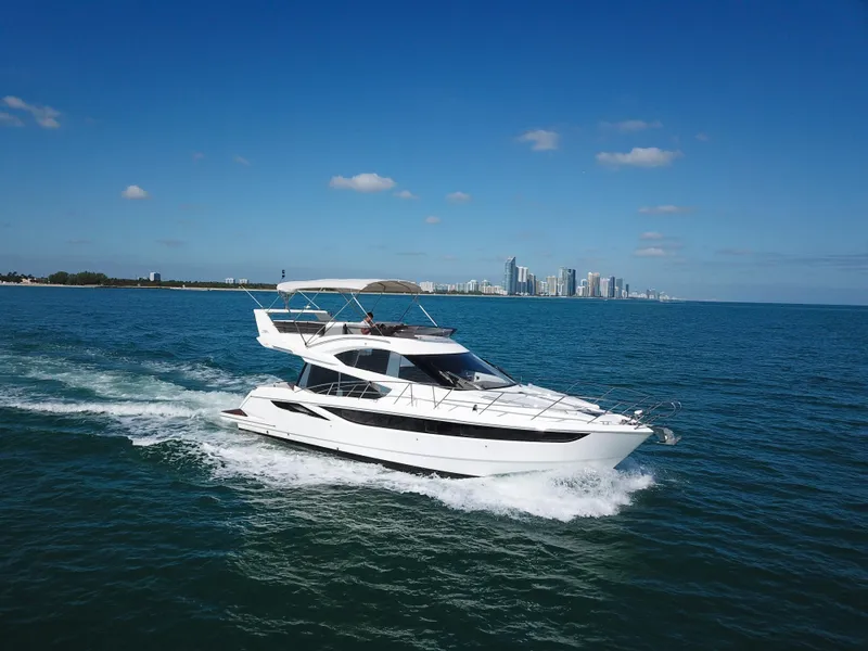 The Image of 2016 Galeon 420 Fly yacht cruising on open water with city skyline backdrop. - 1
