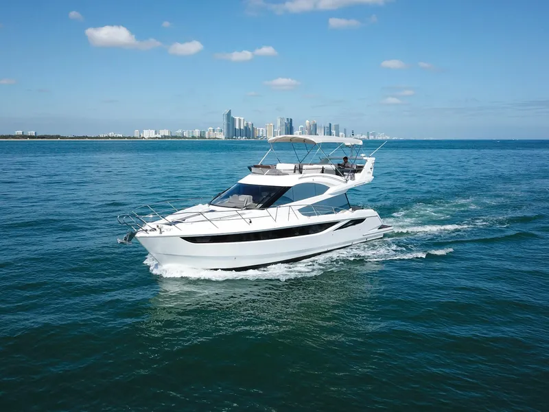 Slide: The Image of 2016 Galeon 420 Fly yacht cruising on blue ocean with city skyline in background. - 4