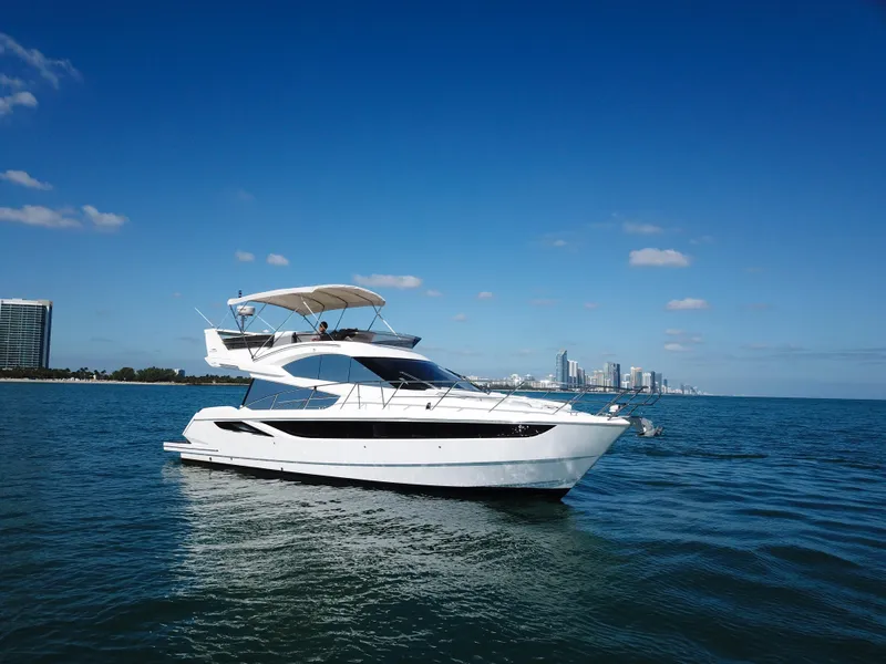 Slide: The Image of 2016 Galeon 420 Fly yacht cruising on open water with city skyline. - 42