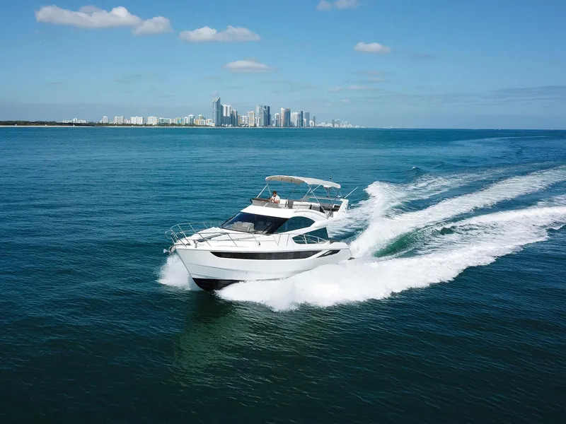 Slide: The Image of 2016 Galeon 420 Fly yacht cruising on open water with city skyline in background. - 6