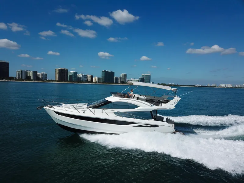 Slide: The Image of 2016 Galeon 420 Fly yacht cruising on open water, city skyline in background. - 8