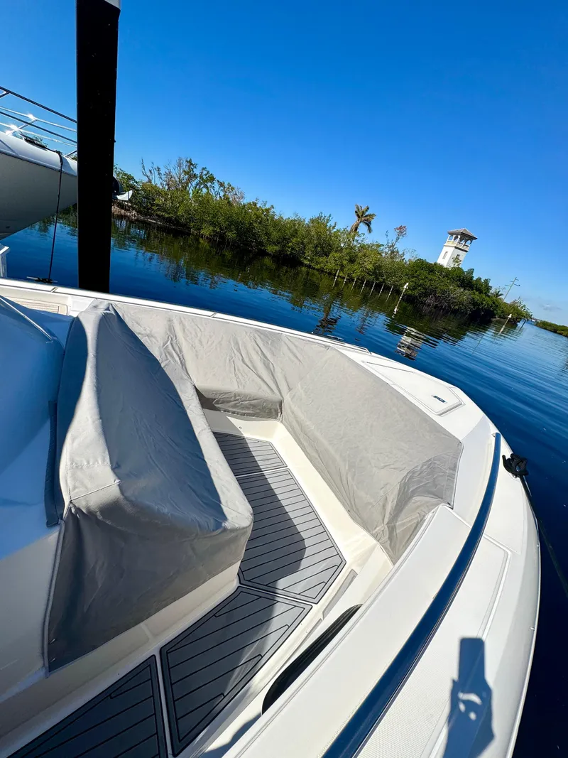 Slide: The Image of Tiara Yachts 38 LS 2018 boat interior with covered seating, docked by lush greenery. - 11