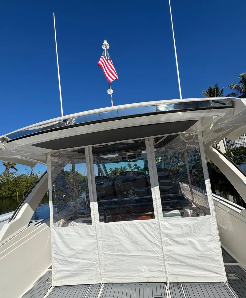 Slide: The Image of 2018 Tiara Yachts 38 LS with American flag, clear enclosure, and sunny sky. - 21