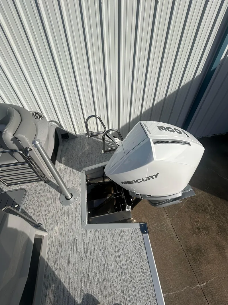 Slide: The Image of 2025 Bennington Q 27 boat with Mercury outboard motor, docked near metal siding. - 11