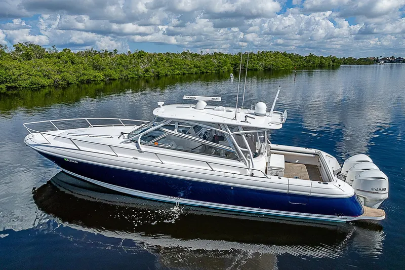 Slide: The Image of 2016 Intrepid 430 Sport Yacht on calm water, surrounded by lush greenery. - 12