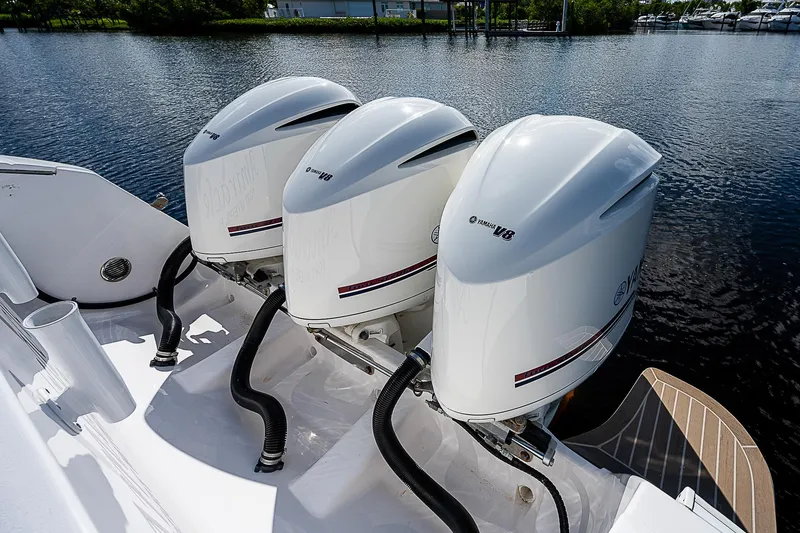 Slide: The Image of Three powerful outboard engines on a 2016 Intrepid 430 Sport Yacht, docked by the water. - 45