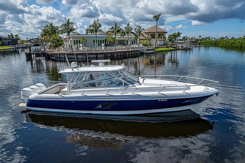 Slide: The Image of 2016 Intrepid 430 Sport Yacht on a serene waterway, surrounded by lush greenery and luxury homes. - 8