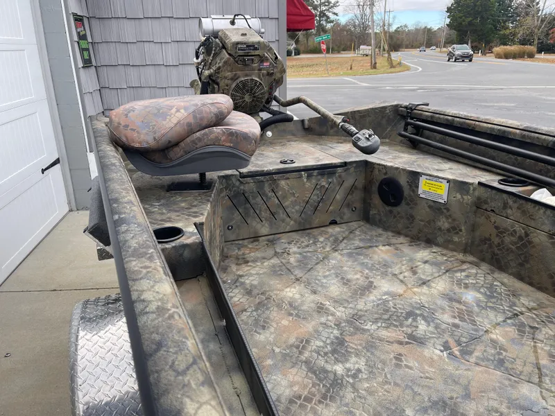 Slide: The Image of 2025 Excel Eclipse boat interior with camouflage design and motor, parked near a road. - 12