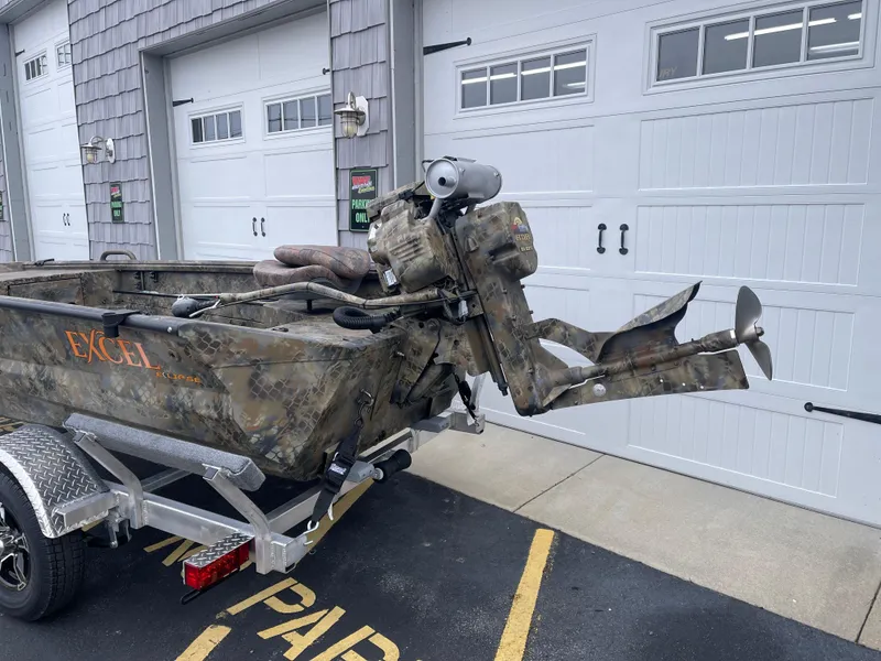 Slide: The Image of 2025 Excel Eclipse boat with camo design on a trailer, parked near garage doors. - 5