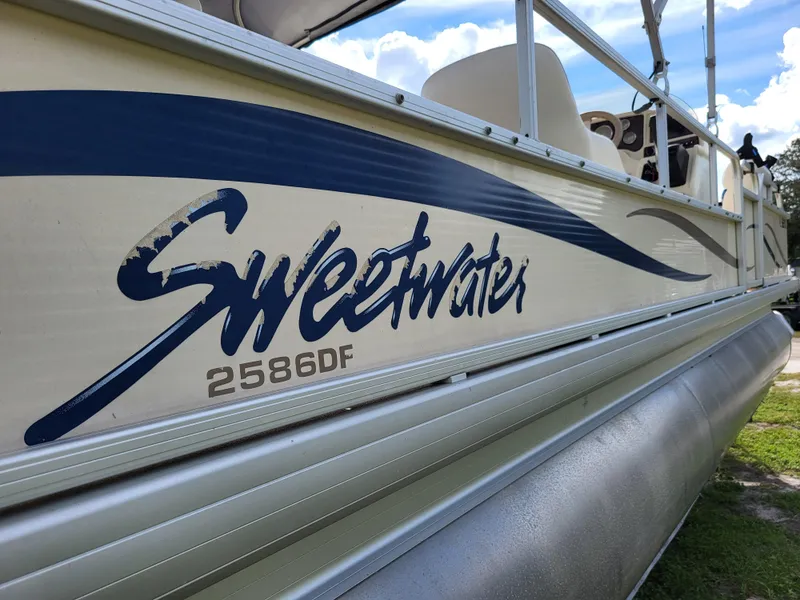 Slide: The Image of 2006 Godfrey Sweetwater 2586DF pontoon boat with blue graphics on the side. - 0