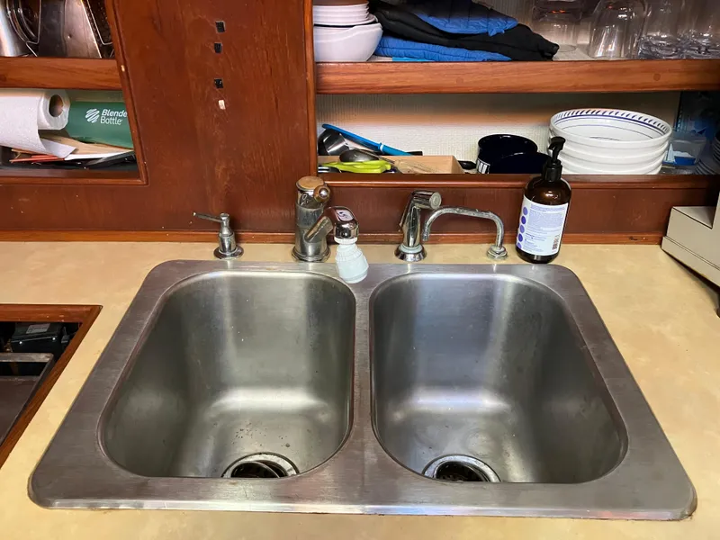 Slide: The Image of Double stainless steel sink in a kitchen with wooden shelves and various dishes. - 17