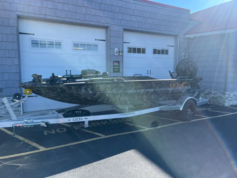 Slide: The Image of 2025 Excel 1860 F4 Shallow Water boat on trailer, parked outside garage. - 1