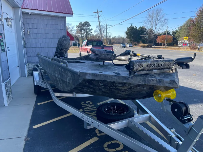 Slide: The Image of 2025 Excel 1860 F4 Shallow Water boat on trailer, parked outside a building. - 4