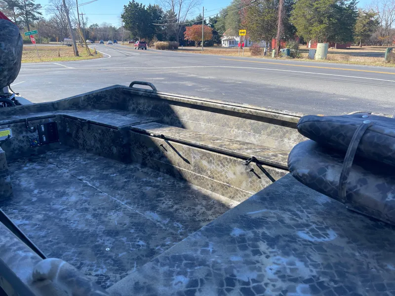 Slide: The Image of 2025 Excel 1860 F4 Shallow Water boat interior, camo design, parked near a road. - 7