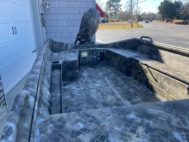 Slide: The Image of 2025 Excel 1860 F4 Shallow Water boat with camouflage interior, parked near a garage. - 8