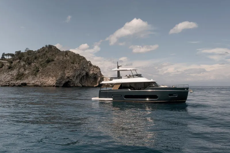 Slide: The Image of 2025 Azimut Magellano 60 yacht cruising near rocky coastline under blue sky. - 28