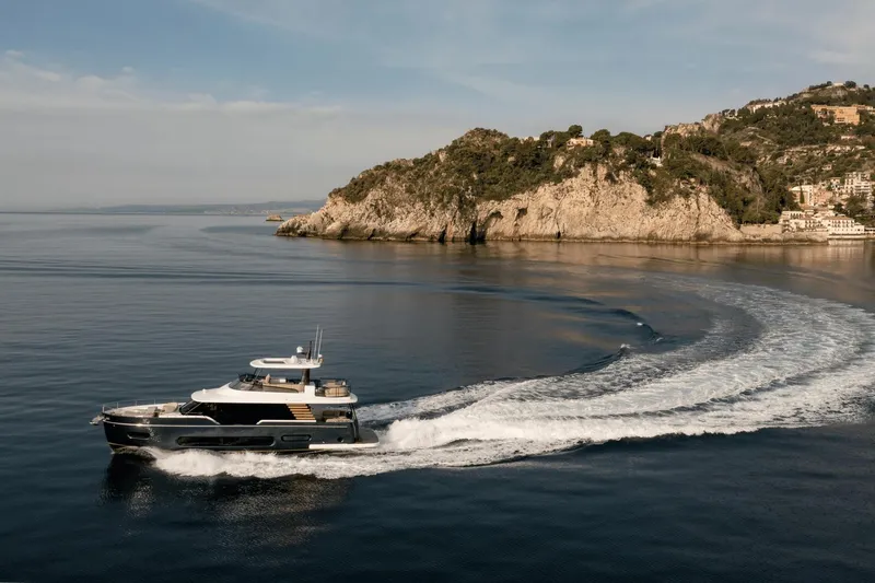 Slide: The Image of 2025 Azimut Magellano 60 yacht cruising near rocky coastline. - 24