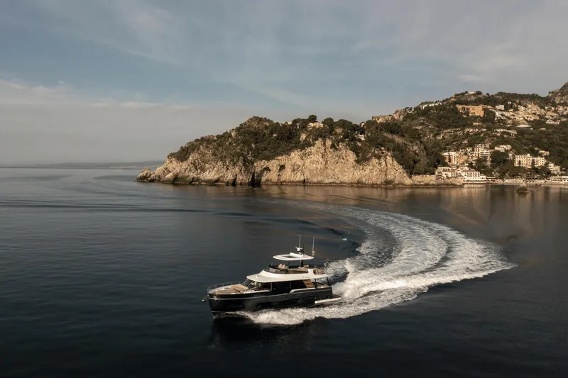 Slide: The Image of 2025 Azimut Magellano 60 yacht cruising near scenic coastal cliffs. - 23