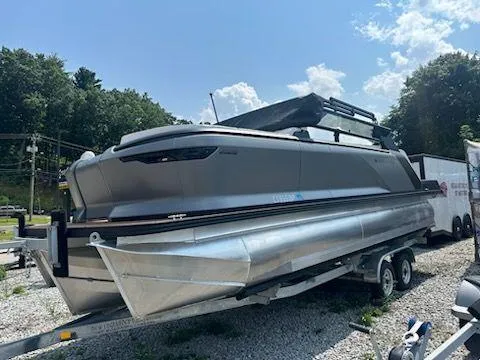 Slide: The Image of 2024 Manitou Explore Switchback 22 MAX pontoon boat on trailer, outdoors. - 3