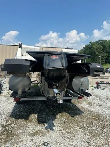 Slide: The Image of 2024 Manitou Explore Switchback 22 MAX boat, rear view, parked on gravel lot. - 4