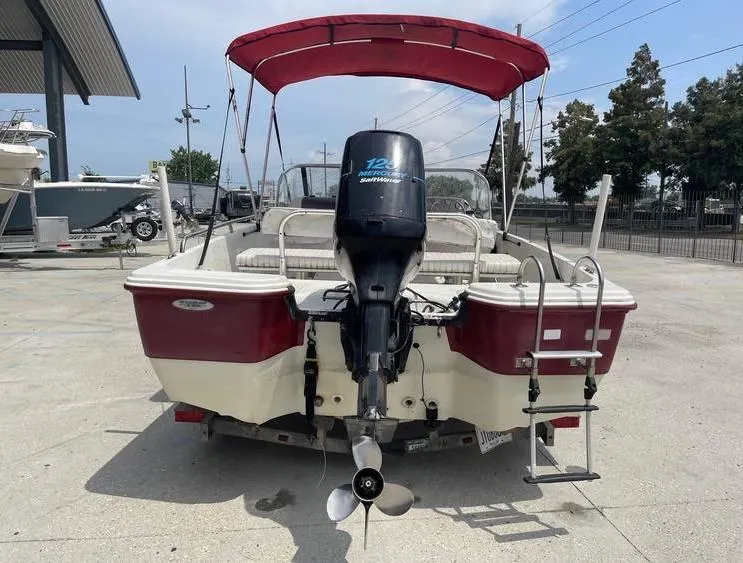 Slide: The Image of 2002 Bay Stealth 1880 BSVW boat with red canopy and outboard motor, parked outdoors. - 4
