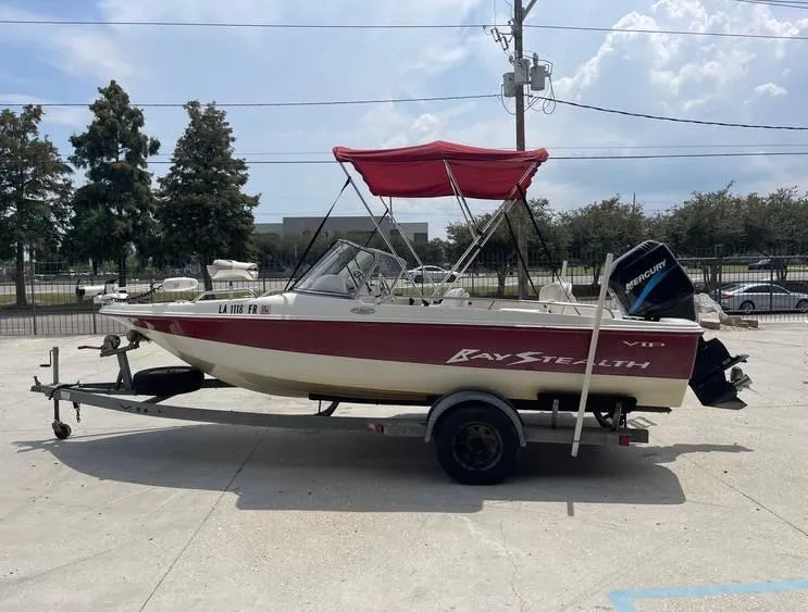Slide: The Image of 2002 Bay Stealth 1880 BSVW boat with red canopy on trailer, parked outdoors. - 6