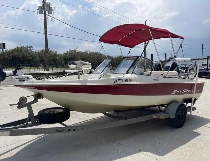 Slide: The Image of 2002 Bay Stealth 1880 BSVW boat with red canopy on trailer, parked outdoors. - 7
