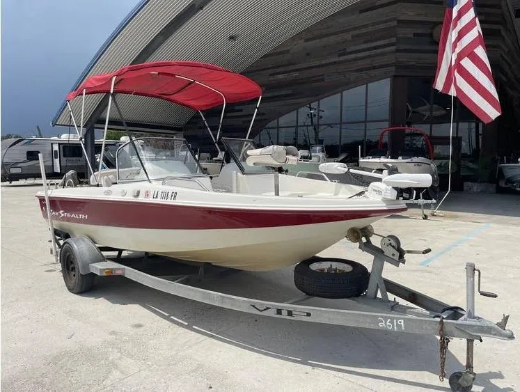 Slide: The Image of 2002 Bay Stealth 1880 BSVW boat with red canopy on trailer, parked near a building. - 9