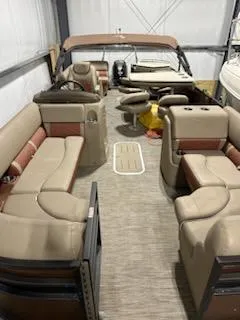 Slide: The Image of 2020 Bennington 23SPDXP pontoon boat with beige and red seating in a storage facility. - 2