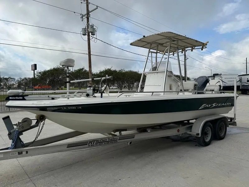 Slide: The Image of 2001 Bay Stealth 2230 boat on trailer, parked outdoors under cloudy sky. - 2