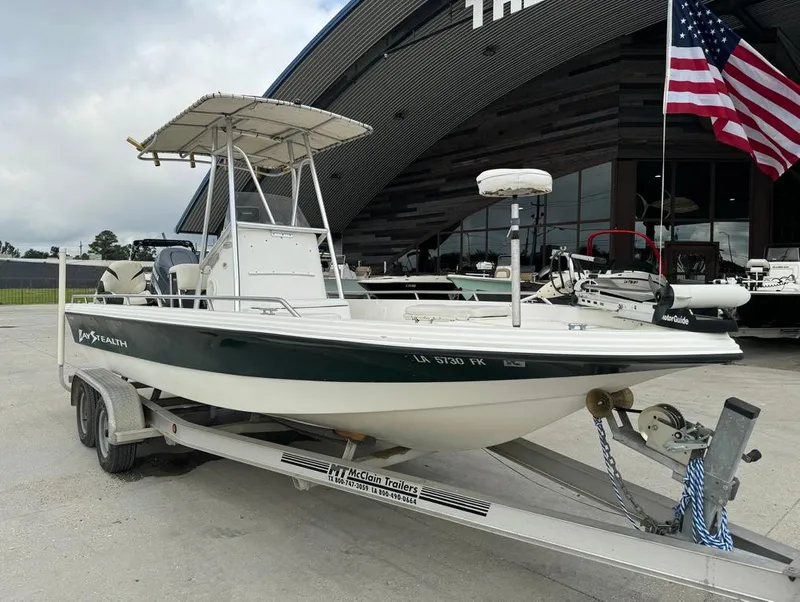 Slide: The Image of 2001 Bay Stealth 2230 boat on trailer, parked outside with American flag. - 4