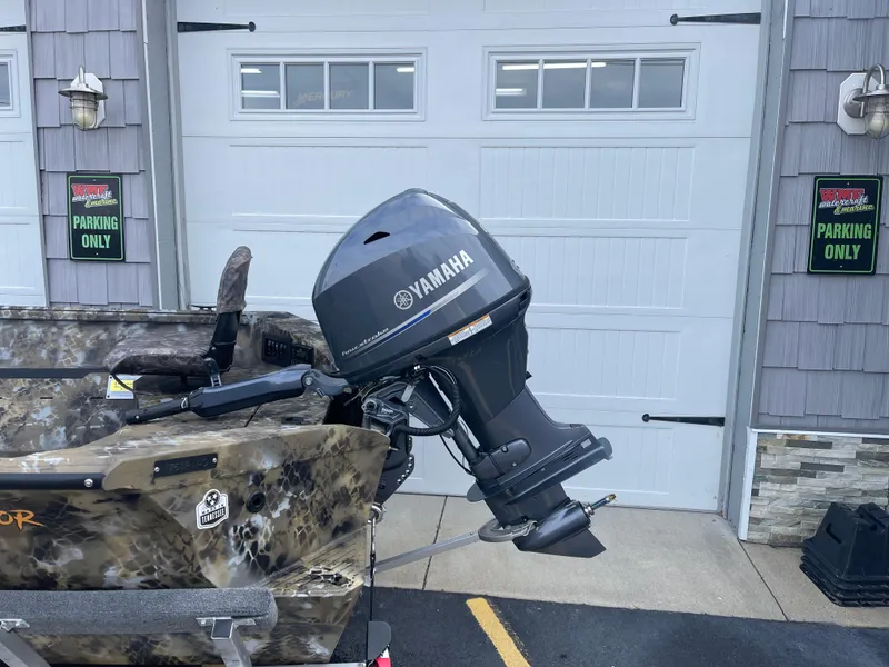 Slide: The Image of 2025 Excel 1751 River Warrior boat with Yamaha outboard motor, parked near garage. - 12