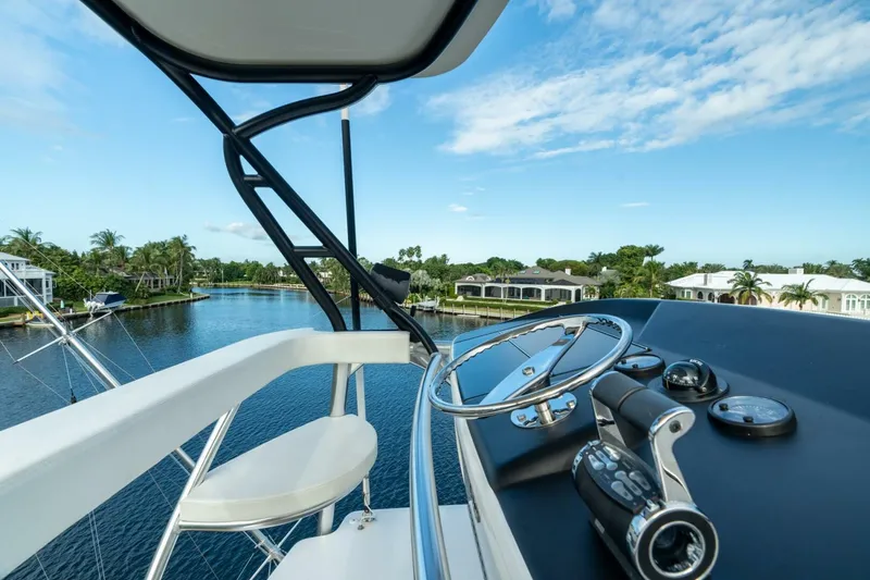 Slide: The Image of 2021 Viking 68 Enclosed Bridge Convertible yacht helm with scenic waterfront view. - 12