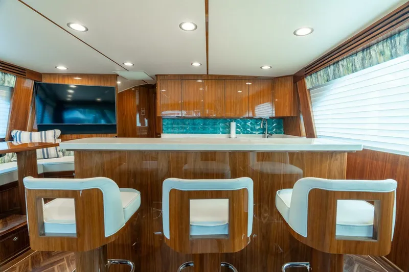 Slide: The Image of Luxurious interior of 2021 Viking 68 Enclosed Bridge Convertible yacht with modern bar seating. - 15