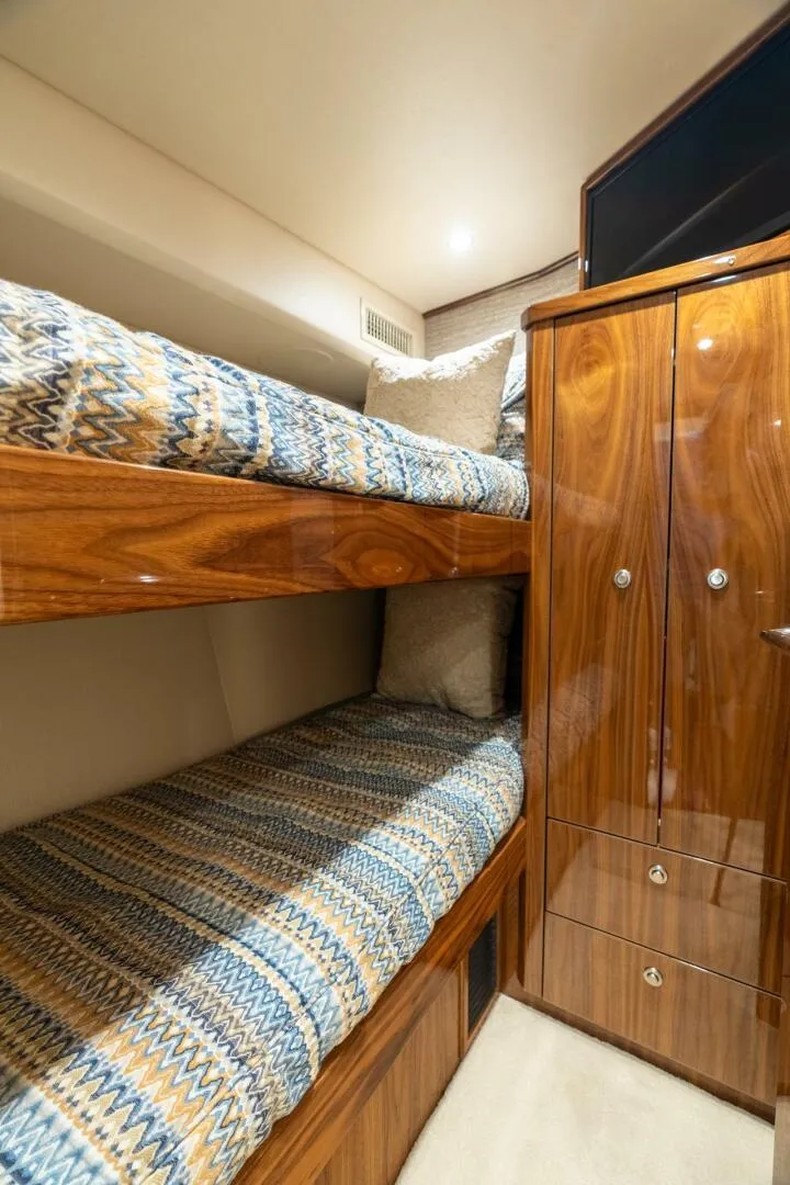 Slide: The Image of Interior of 2021 Viking 68 Enclosed Bridge Convertible with wooden bunk beds and cabinetry. - 25