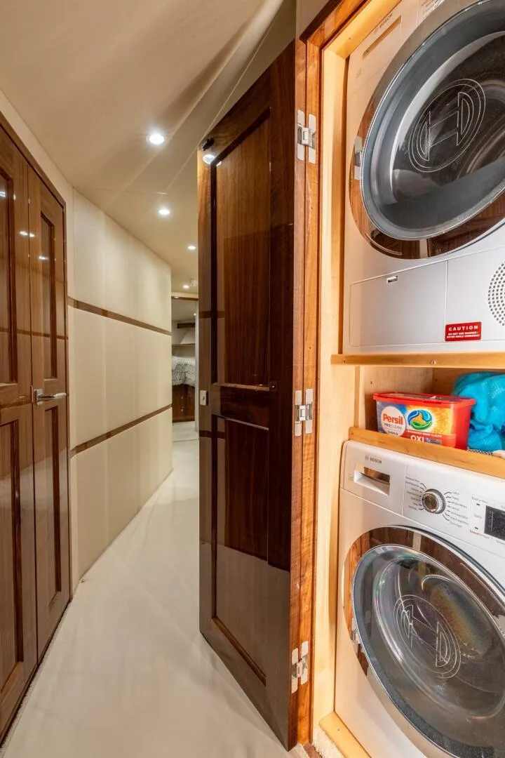 Slide: The Image of Laundry area inside 2021 Viking 68 Enclosed Bridge Convertible yacht, featuring modern appliances. - 30